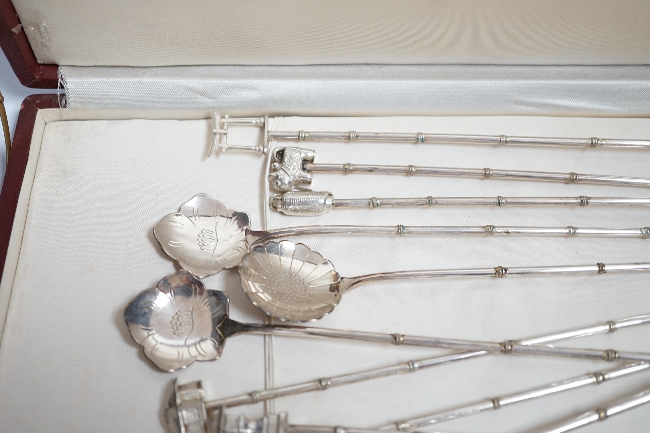 A cased set of twelve Japanese? white metal cocktail spoon, with differing terminals, 21.1cm.